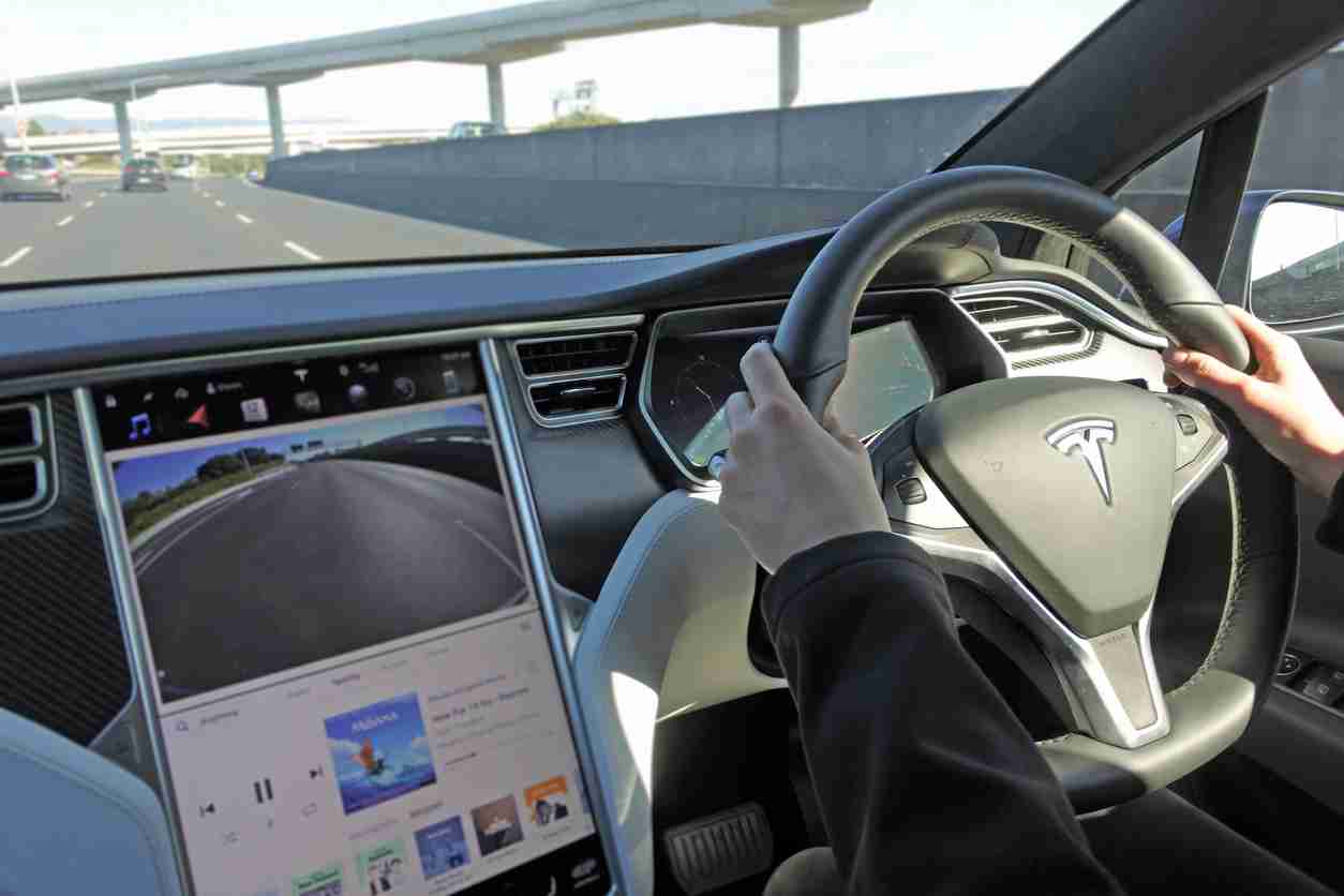 Person driving a Tesla plug-in electric car Model X on a motorway